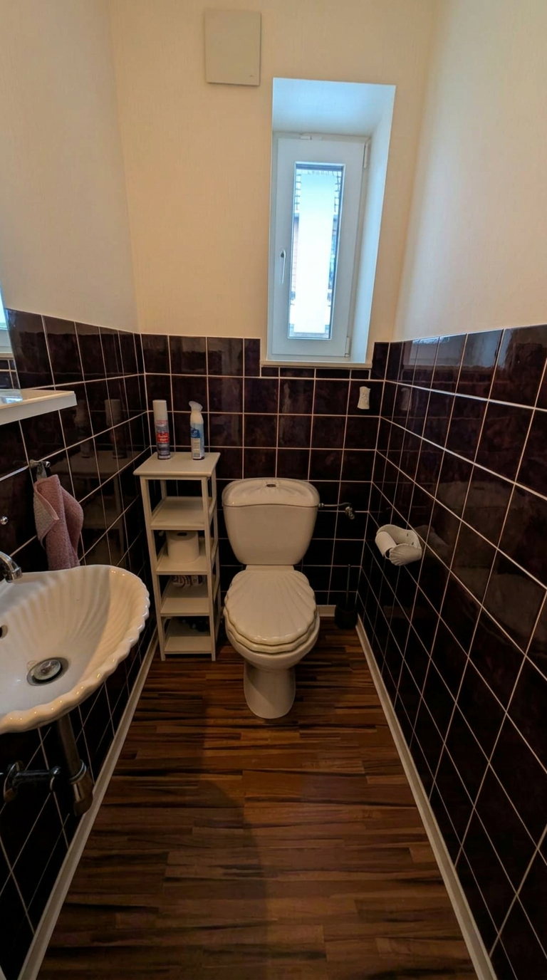 Gäste-WC vor der Sanierung mit dunklen Wandfliesen und altem Waschbecken
